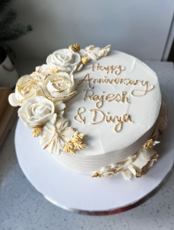 White anniversary cake with gold roses